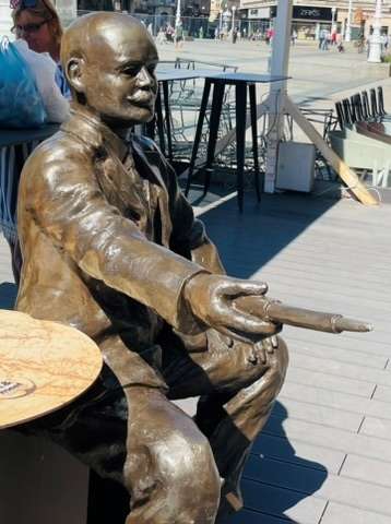Statue of famous Croatian man sitting next to a table in Zagreb